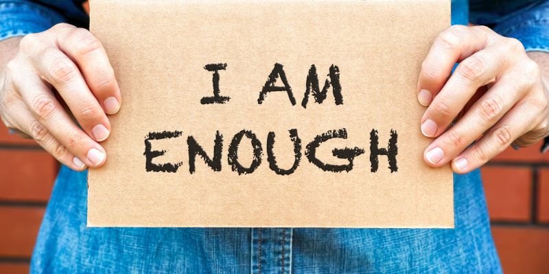 Someone holding a sign that reds I AM ENOUGH.