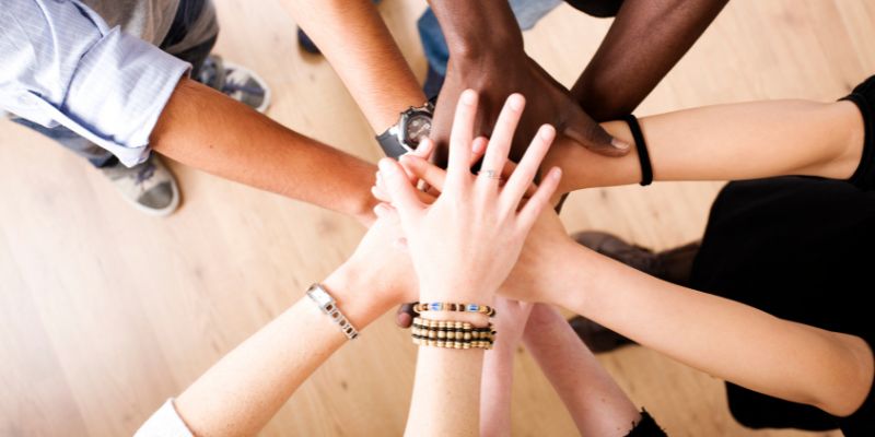 People with their hands on top of each others hands in a circle