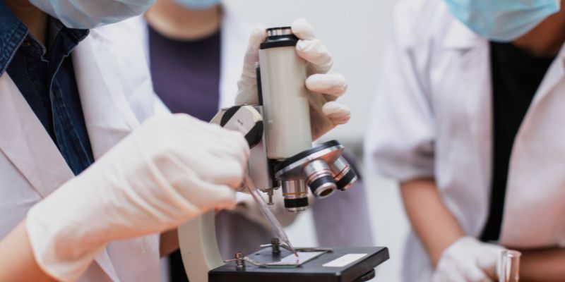 Scientists surrounding a microscope