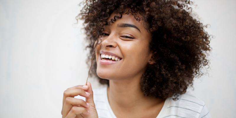 Close up Smiling Young African American Woman Pulling Curly Hair