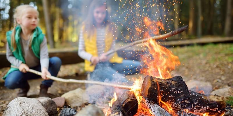 Cute little girls roasting Hotdogs on sticks at Bonfire. 