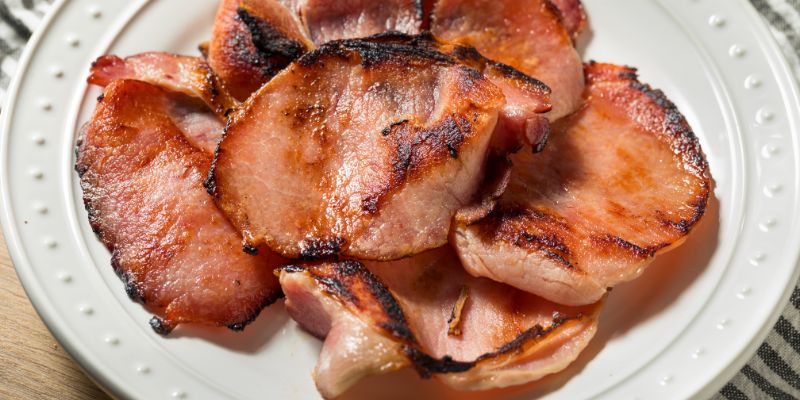 Cooked Canadian bacon on white plate