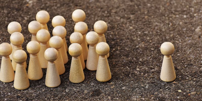 A wooden person with many other wooden people behind it.