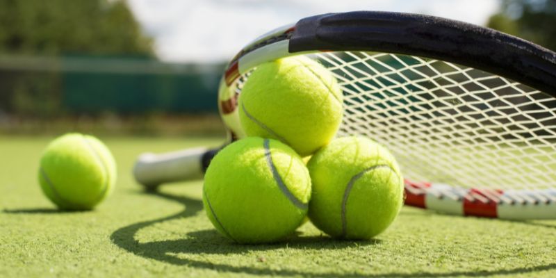 A close up of a tennis racket and tennis balls on a tennis court.