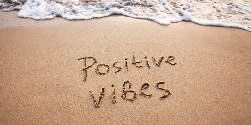 Positive vibes written on the sand on a beautiful beach