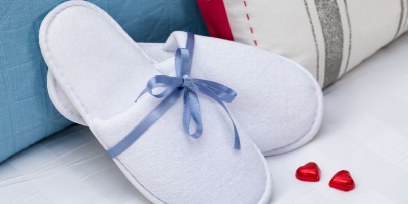 Comfy slippers on a hotel bed.