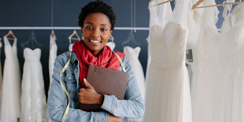 A wedding planner with wedding gowns behind her.