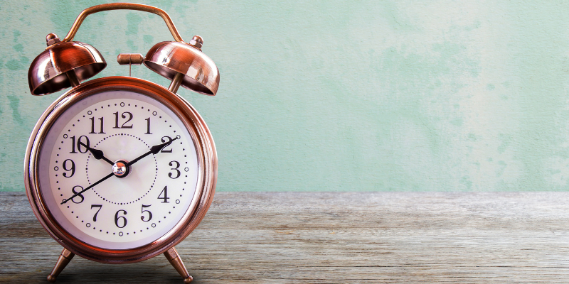 A clock on a natural wood surface and a distressed sea green backgroun