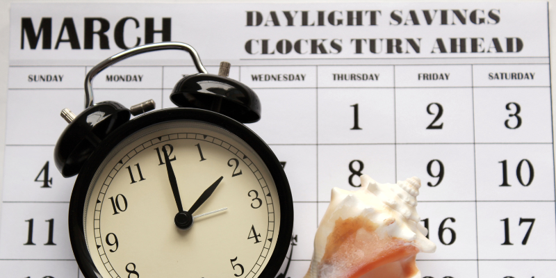 A clock and a March calendar that reads "DAYLIGHT SAVINGS CLOCKS TURN AHEAD"
