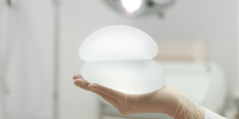 Someone holding two breast implants in one hand