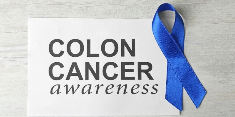 a paper with colon cancer awareness written on it next to a blue ribbon