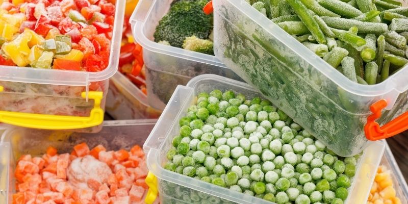 Storage containers each filled with a variety of frozen vegetables