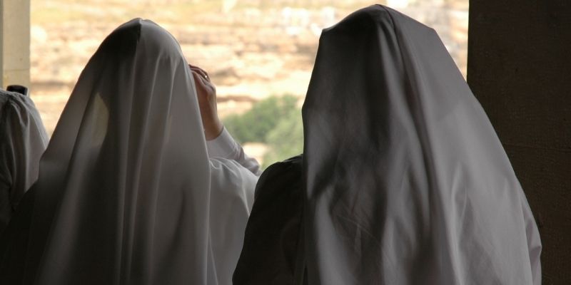 Two catholic sisters with her back turned to the camera.