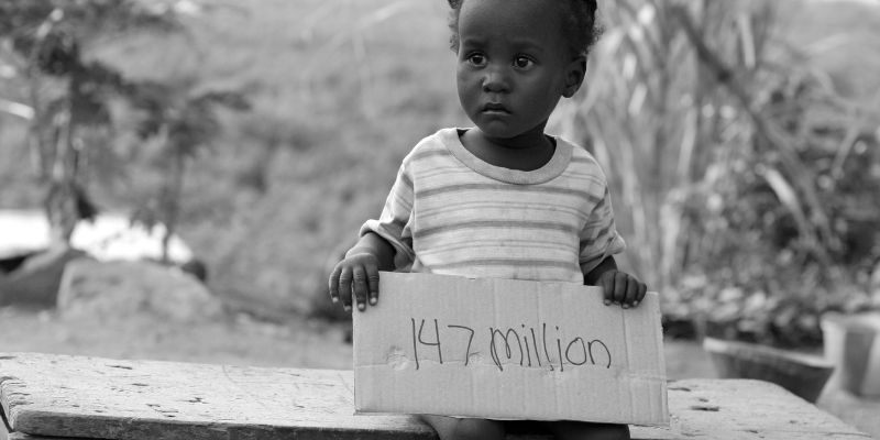An orphan holding a sign that displays the number of orphans in Africa